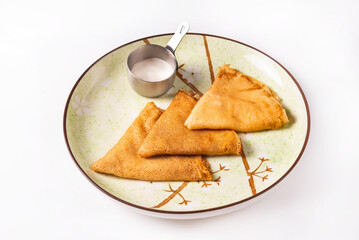 three pancakes with sour cream on a white background