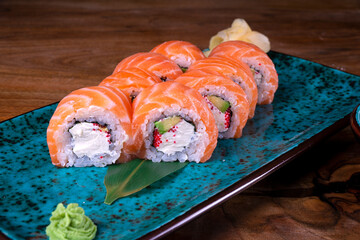 Sushi roll with salmon, avocado and cheese laid out on a black plate. Sushi menu. Japanese food.