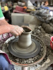  working in a pottery studio throwing a pot.