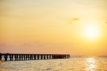 Obraz premium Pier on the sea shore at sunset time.