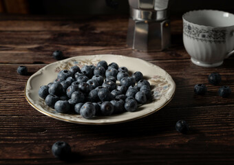 Fototapeta na wymiar Blueberry plate, berries and coffee pot with mug for breakfast or snacks, dark food photography