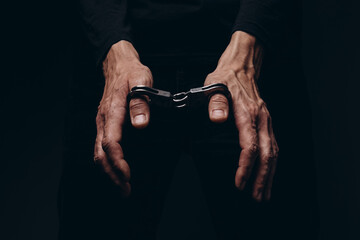 A man in handcuffs on a black background.
