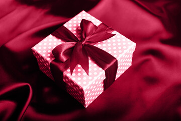 Magenta gift box with a bow on a magenta background. Holiday greeting card.