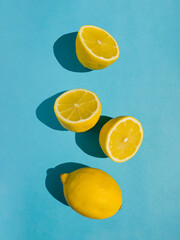 Juicy whole and half lemon and slices on bright pastel blue background. Minimal top view summer concept. - 550940574