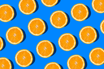 Summer flat lay pattern made with fresh orange fruit slices on vibrant blue background. Minimal sunlight concept with sharp shadows. - 550940712