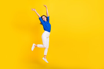 Fototapeta na wymiar Full length photo of sweet pretty lady wear blue shirt rising hands arms jumping high empty space isolated yellow color background