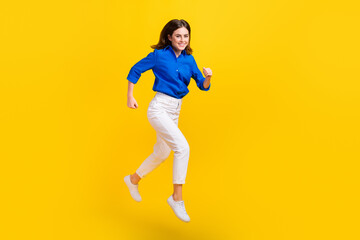 Fototapeta na wymiar Full length photo of pretty excited lady wear blue shirt jumping high running fast isolated yellow color background