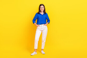 Full length photo of adorable charming girl dressed blue shirt standing arms pockets isolated yellow color background