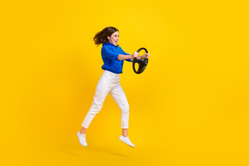 Full length photo of pretty charming lady wear blue shirt jumping high riding auto isolated yellow color background