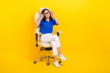 Fototapeta na wymiar Full body length photo of manager lady wear blue shirt white pants sit chair touch glasses look empty space isolated on yellow color background