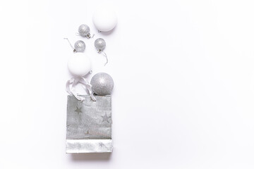 Festive Christmas and New Year shopping concept. Silver gift bag and shining balls on white background top view.