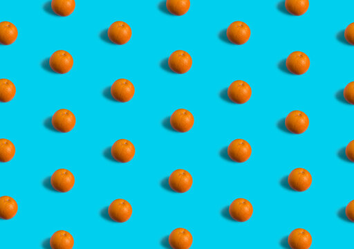 Summer flat lay pattern made with fresh orange fruit on teal blue background. Minimal concept with soft shadows.