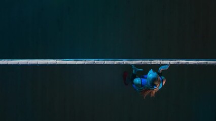 Two young female athletes playing volleyball on the playground in blue light. Top view of woman serving ball and an opponent hitting the ball and rejoicing in victory.