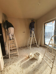 Workers plaster walls in a new house