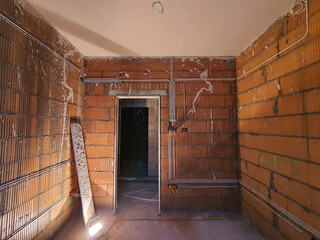 Construction of a new house.  Red brick walls. Electrical wires fixed on the walls