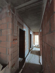 Brick walls in a newly built house. On the walls attached electrical wires. Construction of a new house.