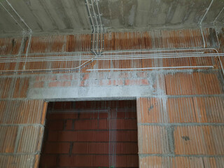 Brick walls in a newly built house. On the walls attached electrical wires