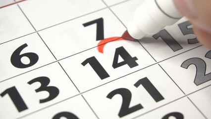 Writing RED HEART on 14th February on calendar with a red marker. The concept of Valentine's day