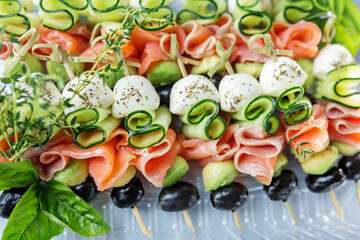 Appetizers with red fish, avocado, mozzarella and cucumbers close-up. Food and catering concept.