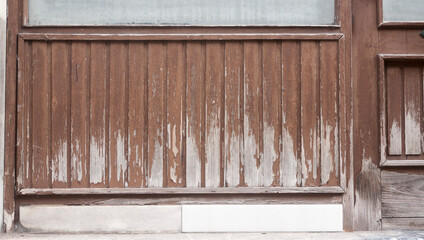 Puerta de madera y cristales de formas cuadradas en fachada deteriorada de edificio urbano