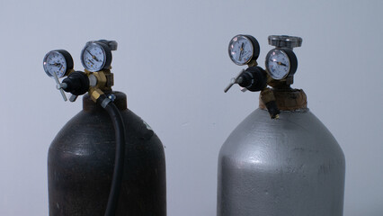 Close-up of pressure sensors on oxygen tanks in the operating room. Metal cylinders with compressed oxygen gas stand against the background of a gray surgery wall.