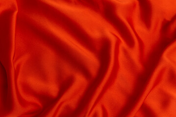 Texture of red fabric close-up. Textile as abstract background. Silk or satin material. Plain bright cloth