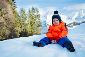 Fototapeta na wymiar Portrait of a happy young boy sit in snow wear winter outfit