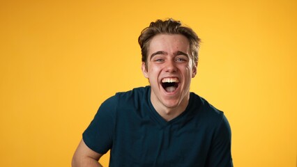 Portrait of laughing smiling happy young hipster man 20s isolated on solid yellow background with...