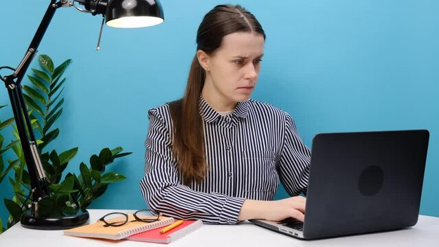 Portrait of strict employee young business woman 20s sit work at white office desk with laptop holding stop gesture hands perpendicularly, posing isolated over blue color background wall in studio