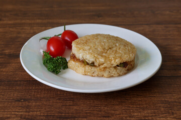 木材背景の白い皿にのせたライスバーガー