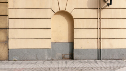 Vano con forma de arco en fachada urbana amarilla y gris