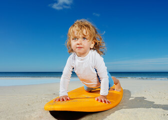 Little toddler girl already practicing push ups on the surfboard