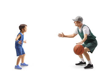 Full length profile shot of a child playing basketball with a senior man