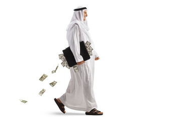 Full length profile shot of an arab man walking with a briefcase full of money