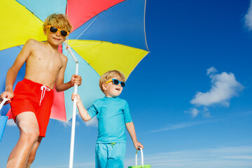Close portrait of boys in sunglasses on a beach under parasol