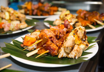 Caribbean-style kebabs of shrimp, sweet yams, bacon, and chicken fillet with pineapple on the leaves