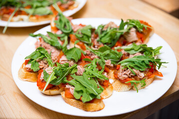 A plate of tuna tapas with stewed red bell peppers and arugula leaves