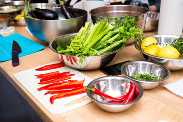raw ingredients, the cooking process. Sliced hot peppers on cutting board, celery stalks in a bowl, lemons, eggplant in iron bowls