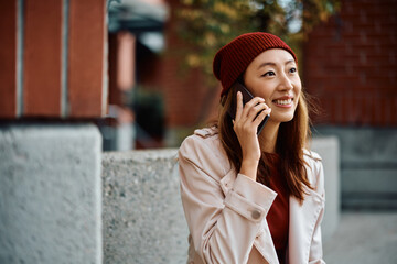 Young happy Asian woman making phone call outdoors.