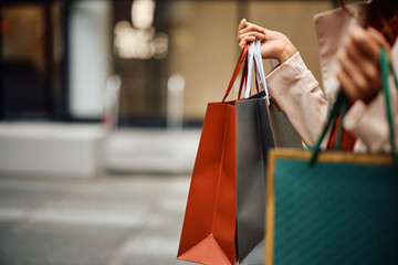 Close up of woman with shopping bags walking on street.
