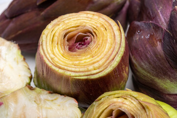 Heads of raw fresh purple romanesco artichoke vegetable heads and pilled hearts