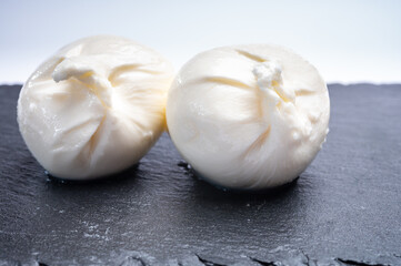 Eating of fresh handmade soft Italian cheese from Puglia, white balls of burrata or burratina cheese made from mozzarella and cream filling