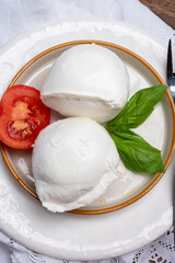 White balls of Italian soft cheese Mozzarella di Bufala Campana served with fresh green basil and red tomato