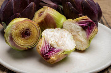 Fototapeta premium Heads of raw fresh purple romanesco artichoke vegetable heads and pilled hearts