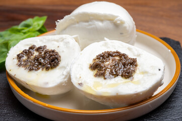 White balls of Italian soft cheese Mozzarella di Bufala Campana stuffed with black truffles mushrooms