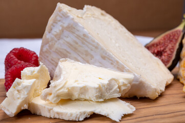 Board with french soft cheese Delice de Bourgogne French cow's milk cheese from Burgundy region of France  served with fresh raspberries