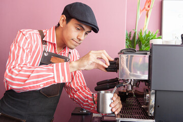 man steaming the milk of a coffee on a expresso machine - obrazy, fototapety, plakaty