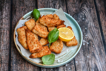   Allasca Pollock Fish  Bites in a crispy Tempura  Batter.Fish and chips .Close up of   crispy breaded  deep fried fish fingers with breadcrumbs s erved with remoulade sauce and  lemon