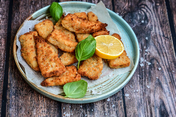   Allasca Pollock Fish  Bites in a crispy Tempura  Batter.Fish and chips .Close up of   crispy breaded  deep fried fish fingers with breadcrumbs s erved with remoulade sauce and  lemon