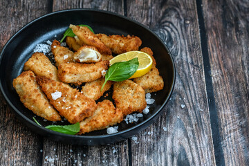   Allasca Pollock Fish  Bites in a crispy Tempura  Batter.Fish and chips .Close up of   crispy breaded  deep fried fish fingers with breadcrumbs s erved with remoulade sauce and  lemon